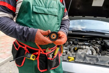 Araç kemeri olan tamirci araba motoruna karşı araç filtresi gösteriyor.
