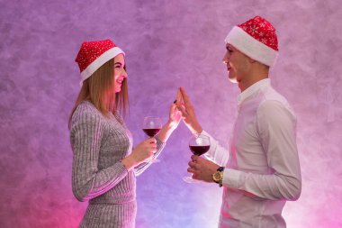 Mutlu, genç çift, şarap kadehleri ve Noel Baba şapkalarıyla Sevgililer Günü 'nü kutluyorlar.