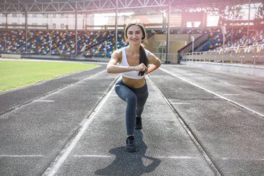 Spor kıyafetli bir kadın stadyumda sabah koşusu yapıyor.