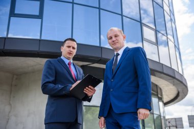 Takım elbiseli iş ortakları açık havada anlaşma yapıyor.