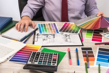 Modern ev projesi fikri üzerinde ofiste çalışan bir tasarımcı. Daire çizimi ve renk seçimi