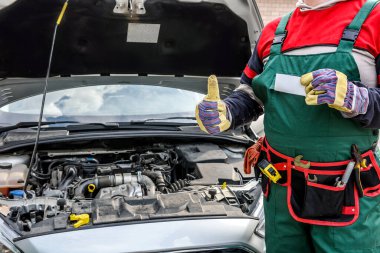 Araba servisi reklamı. Araba tamircisi baş parmağını gösteriyor. Kaputu açık araba.