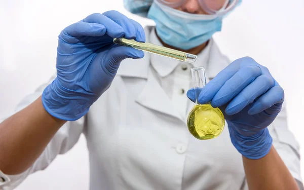 Chemist in protective glasses and uniform with test tube