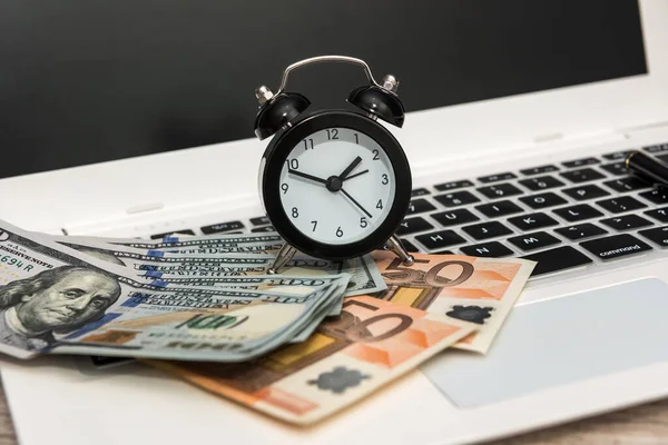 money and clock on laptop