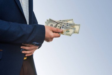 Başarılı bir iş adamı Amerikan dolarını beyaz arka planda tutuyor.