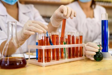 Laboratuvarda deney yapan kimyasal ekipman ve iki kimyager.