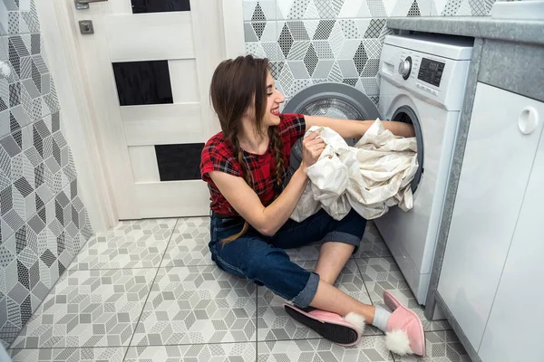 woman  loads the laundry clothes into washing machine.