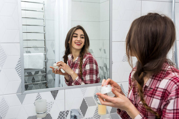 Beautiful woman applying cleansing moisturizing skin cream on face after bath. Skincare