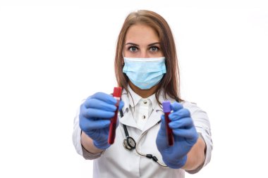 Maskeli doktor, beyaz üzerinde kırmızı madde bulunan test tüplerini inceliyor.