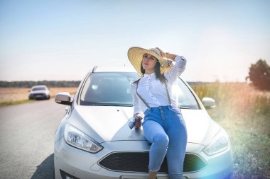 Yolun kenarına park etmiş, arabanın yanında güzel bir genç kadın. Seyahat etmenin zevki.