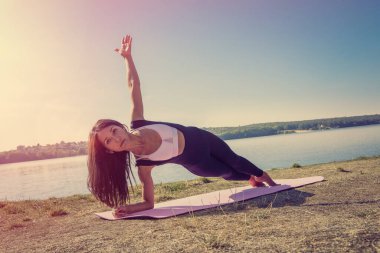 Genç bir kadın sabah erkenden bacaklarını açıyor. Açık havada çalışma saatinden önce..