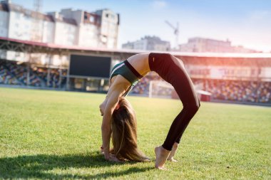 Stadyumdaki çimenlerde jimnastik yapan güzel bir kız..