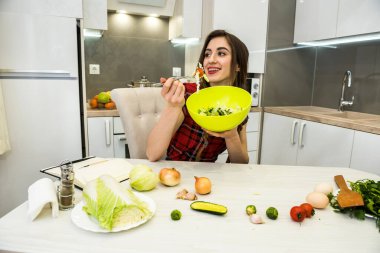 Sağlıklı bir yaşam için mutfakta sebze salatası yiyen bir kız.