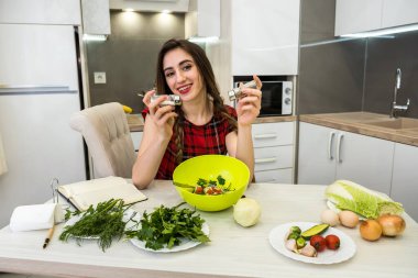 Genç kadın sebzeli salata hazırlıyor. Daha lezzetli olsun diye tuz ve biber ekliyor..