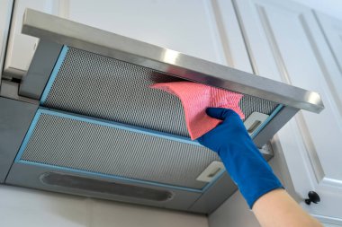 Kadın eli kauçuk koruyucu kapüşonlu, mutfakta bez parçasıyla.