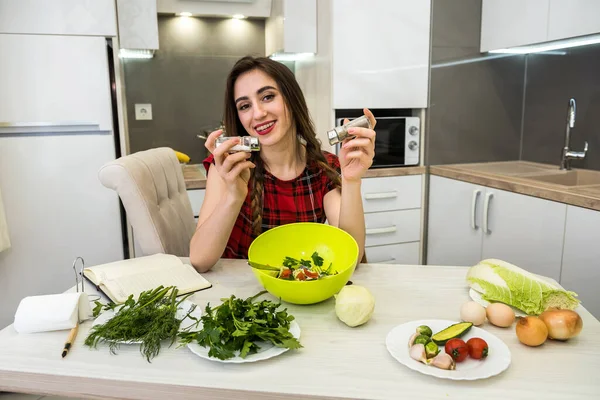 Genç kadın sebzeli salata hazırlıyor. Daha lezzetli olsun diye tuz ve biber ekliyor..