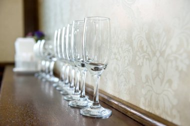 Duvara karşı ahşap masada şampanya için parlak bardaklar. Kutlama konsepti