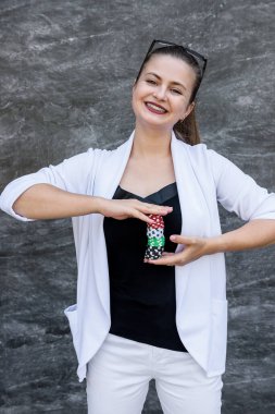 Kumar konsepti. Güneş gözlüklü bir iş kadını elinde poker fişleri ve soyut arka planda poz veriyor.