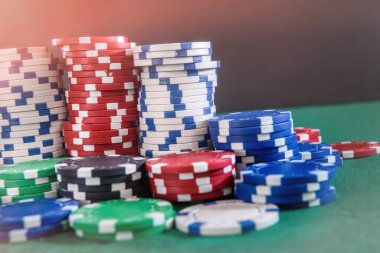 Kumar teması. Yeşil masadaki destelerde renkli çipler. Yakın plan.