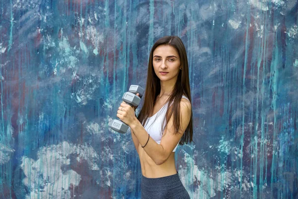 快乐的年轻女子 哑铃在现代彩绘墙前做运动 — 图库照片