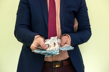 Takım elbiseli bir adam büyük miktarda Ukrayna parası tutuyor ve gelirini gösteriyor. - Evet. Yeni banknotlar 1000 ve 500 Hryvnia