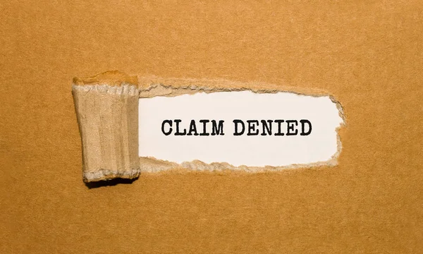 Yırtık kahverengi kağıt arkasında görünen CLAIM DENIED metni