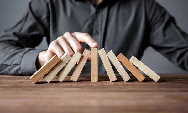 Uomo d'affari che ferma l'effetto domino con il dito. Concetto di sicurezza e assicurazione . — Foto Stock