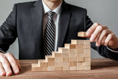 İşadamı el adım merdiven olarak yığma ahşap bloklar kalkınma düzenlenmesi. İş büyüme başarı süreci, plan ve strateji iş.