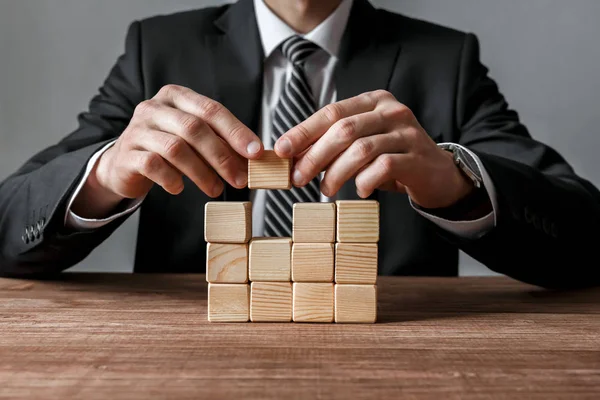 Close-up de empresário fazendo uma estrutura com cubos de madeira. Conceito de sucesso e estratégia empresarial . — Fotografia de Stock