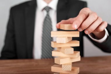 İş adamı bir kuleye tahta blok yerleştiriyor. Planlama, risk ve iş stratejisi kavramları.