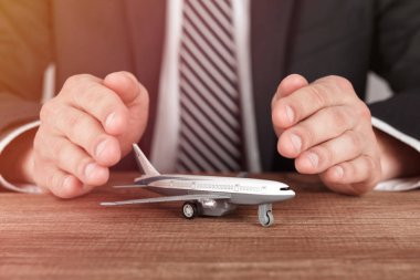 Uçak model koruma jesti elinde çevrili. Havayolu emniyet, güvenlik ve sigorta kavramı.
