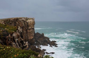 Kayalıklar ve okyanus dalgaları. Mavi su arkaplanı.