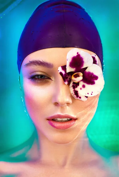 Woman laying in water with orchid on face