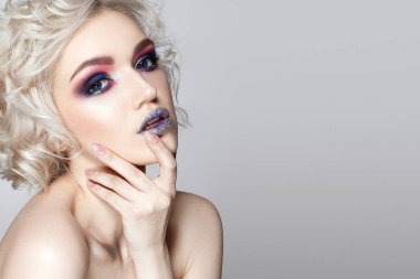 Genç kıvırcık model gri arka plan üzerinde poz moda parlak makyaj ile