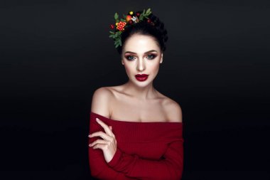 Portrait of young brunette model with fashionable red lips makeup and wreath with leaves and berries  clipart