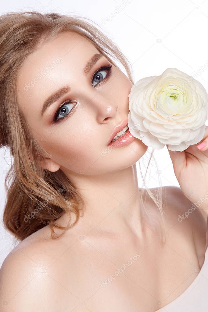 Portrait of young model with natural makeup and ranunculus on white background