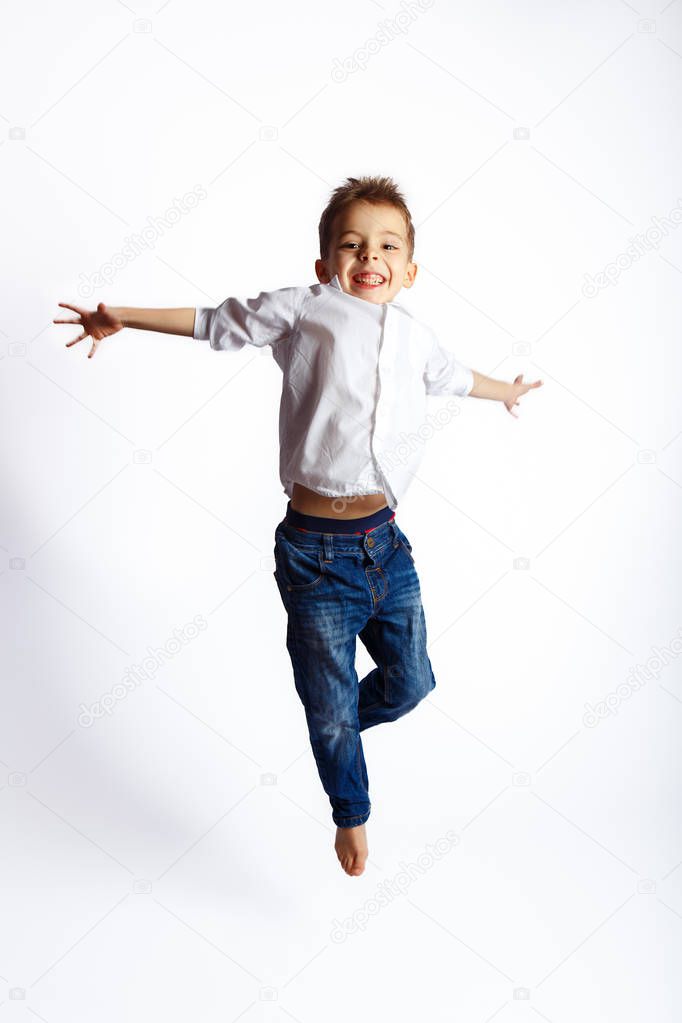 Boy in white shirt jumping on white background in studio