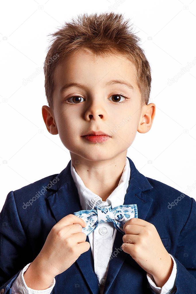 Young boy in suit with bow-tie posing against white background