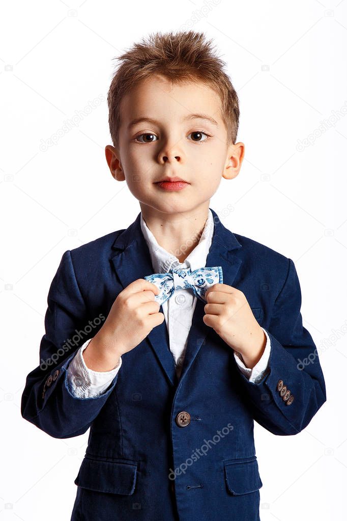 Young boy in suit with bow-tie posing against white background