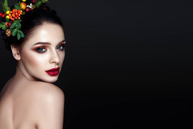 Portrait of young brunette model with fashionable red lips makeup and wreath with leaves and berries  clipart