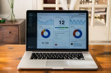 Analitik grafik üzerinde ev iç ahşap masa üstünde belgili tanımlık perde ile gümüş dizüstü bilgisayar
