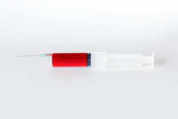 Seringa com líquido vermelho, sangue para injeção sobre branco — Fotografia de Stock