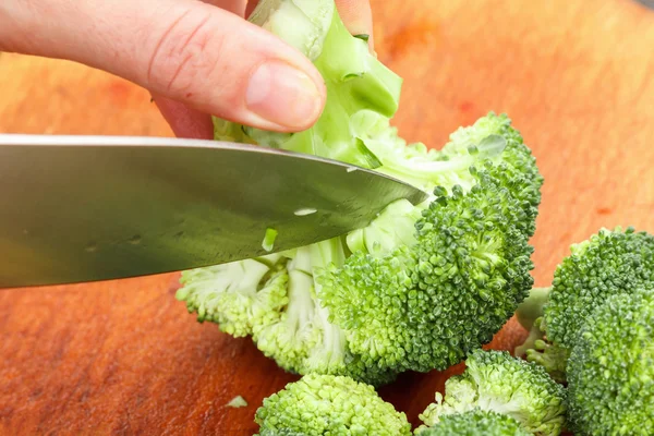 Chef-kok snijden verse groene broccoli voor het koken. Stock-up op winter voedsel. — Stockfoto