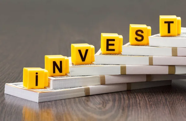 Begreppet investeringar, ord gjort genom skrivelse, bunt dollarsedlar — Stockfoto