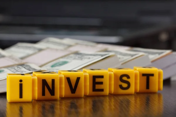 Investimentos conceituais, palavra feita por carta, pilha de notas de dólar — Fotografia de Stock