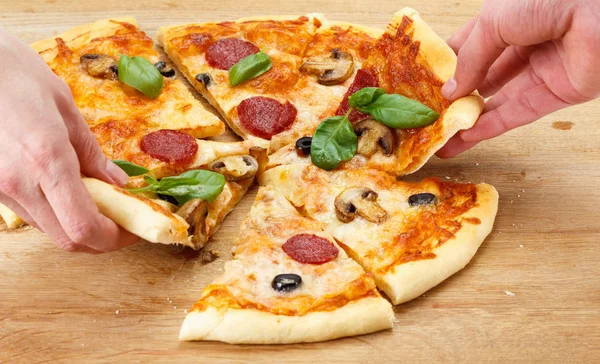 Ludzie biorą plasterki pizzy z ser, pieczarki, salami — Zdjęcie stockowe