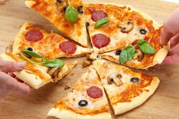 Ludzie biorą plasterki pizzy z ser, pieczarki, salami — Zdjęcie stockowe