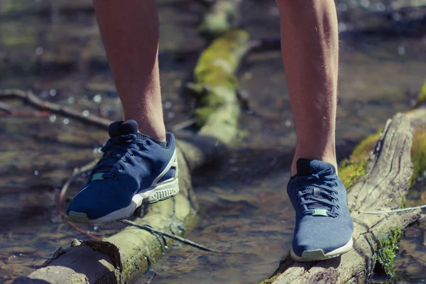 Concetto di viaggio e avventura, gambe da uomo che attraversano un torrente — Foto Stock