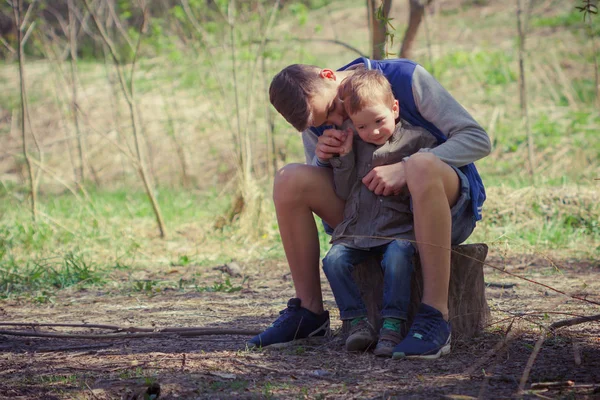 Dos lindos niños sentados en el bosque . —  Fotos de Stock