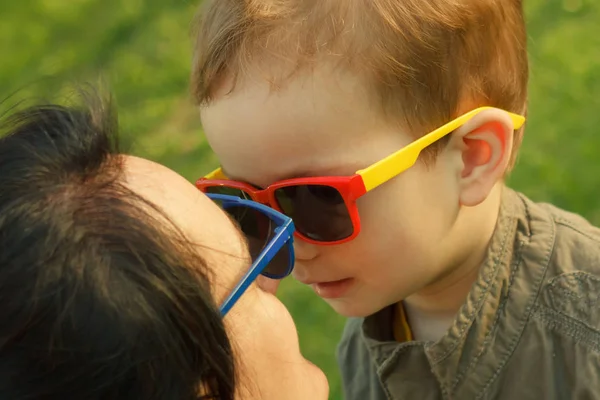 El hijo besa y abraza a su madre en gafas de sol al aire libre . — Foto de Stock